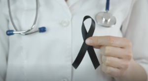 Image of doctor holder a black ribbon to symbolize and support melanoma and skin cancer awareness month